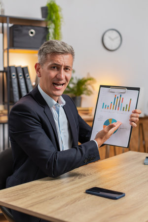 POV of Caucasian businessman working at home office desk showing graphical analytics and talk on...