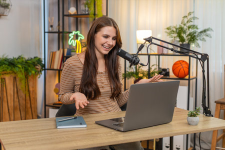 Young woman at home records vlog speaks to studio microphone gives greeting and short intro about...