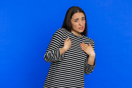 Caucasian woman in striped blouse pointing fingers herself ask say who me no thanks i do not need it, feels innocent, not her fault, fail mistake. Girl isolated on blue backgroundの写真素材