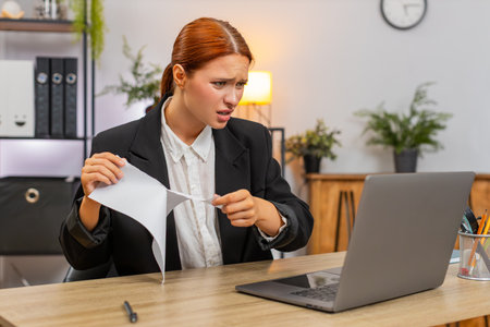 Young businesswoman at home office tears draft report after spotting error and decides fresh start...