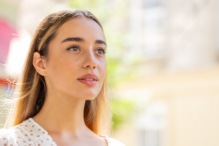 Close-up portrait of happy young woman face smiling friendly open eyes glad expression looking away...
