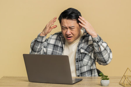Displeased Asian man using laptop typing working, loses becoming surprised sudden lottery results...