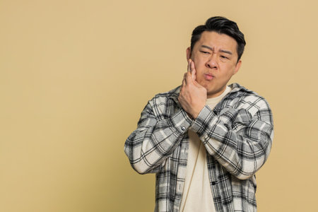 Dental problems. Asian middle-aged man touching cheek, closing eyes with expression of terrible...