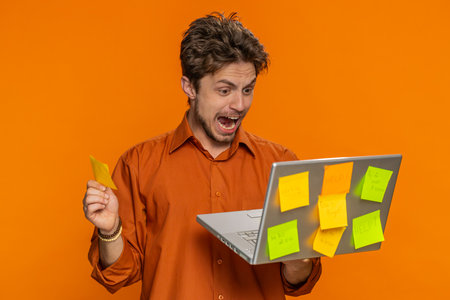 Exhausted freelancer man with pasted sticker notes use laptop computer having concentration problem...