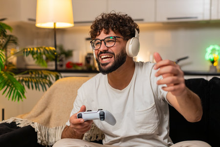 Man at home plays on game console holds joystick leans forward enjoys play sees level score high....