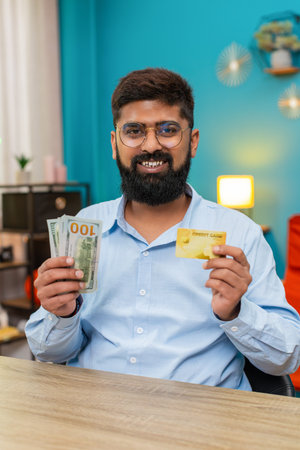 Man at home shows credit card with dollars cash promoting withdrawal loan option displays money...