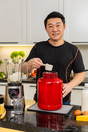 Asian young man pours whey protein into blender with banana and cottage cheese for breakfast shake. Protein smoothie supports muscle weight control fitness energy and clean home diet plan daily good.の写真素材