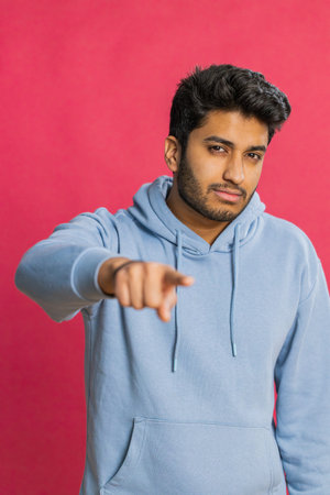 Indian smiling man pointing finger to camera and looking with playful happy expression, making...