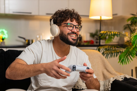 Arabian man at home plays on game console holds joystick leans forward enjoys play sees level score...