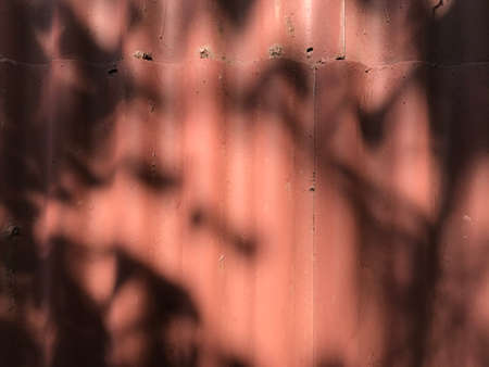 background texture fence of red slate with hard shadows from tree branches.