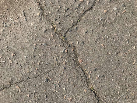 background texture pattern on an old road made of asphalt with trebles and granite rubble.