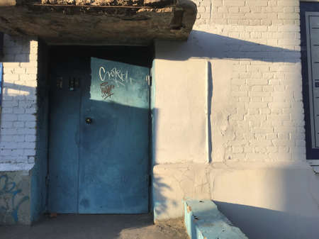 old blue metal doors and a white brick wall with shadows at sunset.