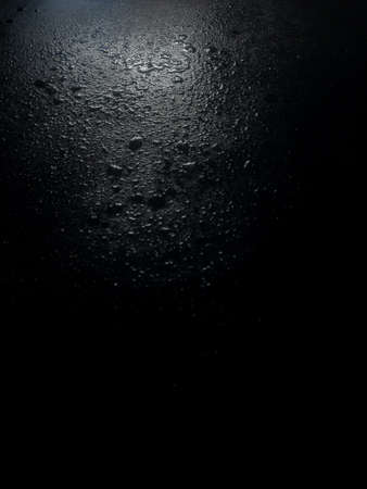 black background water drop on the table with a white spot of light.の写真素材