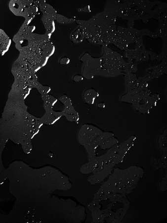 texture background patterns of water spilled on a black flat surface.の写真素材