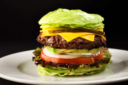 Burger with vegetables and lettuce burger with onion and tomato, dark background. lettuce leaf on top of a hamburger with onion rings, tomato, cheese and burger meat. Cooking concept.の写真素材