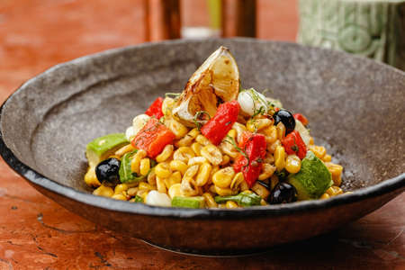 Corn avocado and black olives salad with lime close up side view. avocado salad with tomatoes, cucumbers in bowl.の写真素材