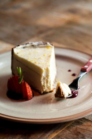 Dessert Cheesecake on a plate with fork and sliced strawberry, side view. piece of cheesecake on a plate and a fork.の写真素材