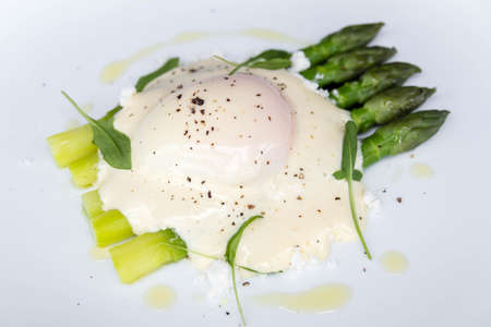 Green asparagus, and cooked poached eggs, hollandaise sauce, on a white plate, close up, isolated.の写真素材