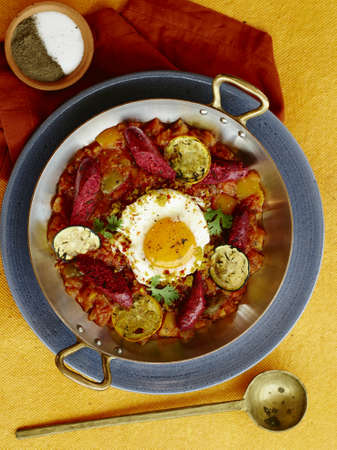 Fried egg sunny side egg with baked vegetables tomatoes eggplants in a pub from above on a table with spoon Shakshuka with pita bread in a pan. Eggs with tomatoes and toast bread in a frying pan.の写真素材
