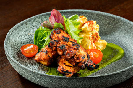 Fried Grilled octopus with salad and salsa sauce on a round plate, close up. A plate of restaurant chef made delicious grilled octopus salad with spices, herbs and lime.の写真素材