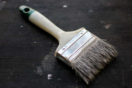 Used 3 inches paintbrush with gray paint on dark backgroundの写真素材