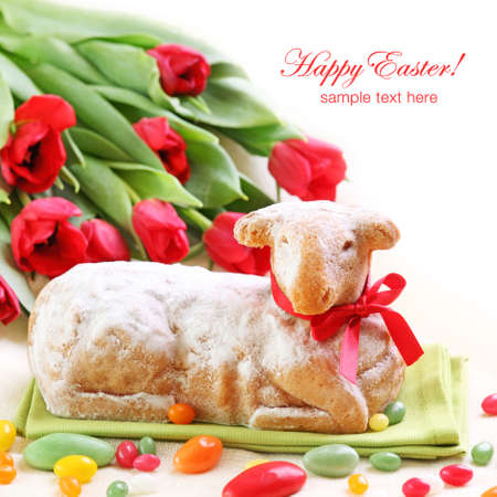 Easter lamb cake and red tulips on white background