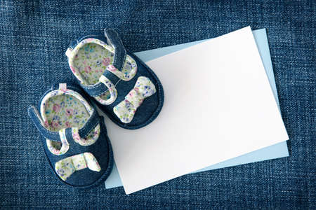 Baby shoes and blank note on blue backgroundの写真素材