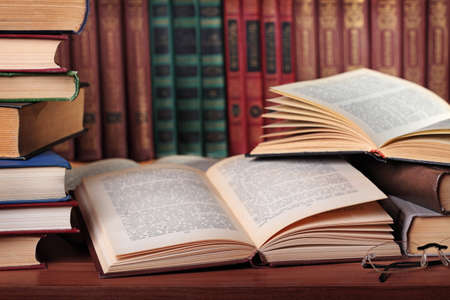 Pile of books with reading glasses on desk