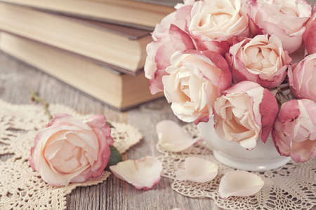 Pink roses and old books on wooden desk