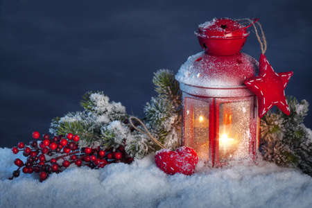 Burning lantern in the snow at nightの写真素材