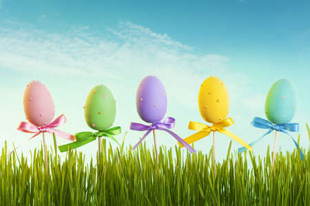 Easter eggs on wooden sticks and green grassの写真素材