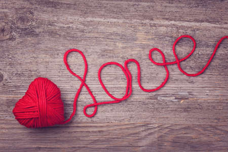 Red heart of red wool yarn on a wooden の写真素材