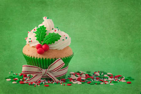 Christmas cup cakes with holly berry on a green backgroundの写真素材