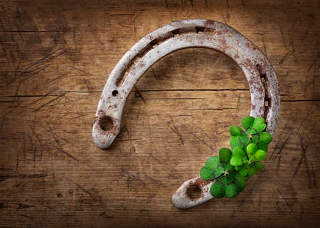 Old rusty horseshoe and four leaf clover on a wooden backgroundの写真素材