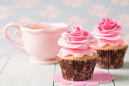 Cupcakes with sweet rose flowers and a cup of teeの写真素材