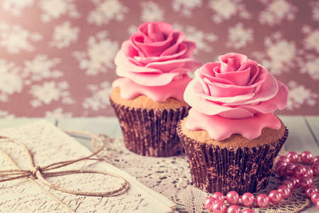 Cupcakes with sweet rose flowers and a letterの写真素材