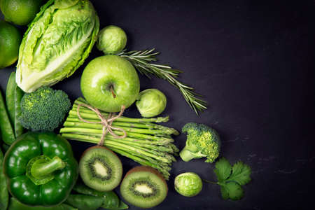 Green healphy vegetables and fruits on a black slatesの写真素材