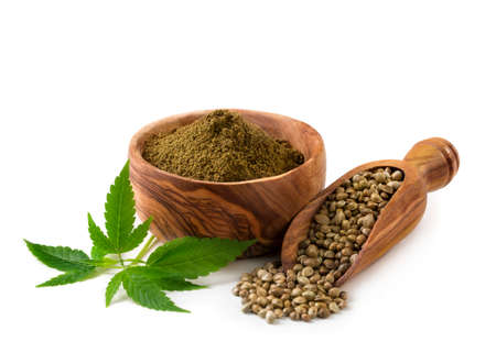 Hemp seeds and flour with a green leaf on a white backgroundの写真素材