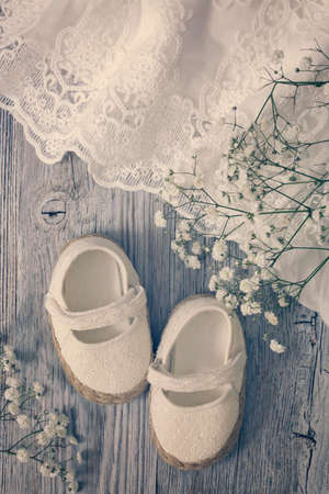 White baby girl shoes on a wooden backgroundの写真素材