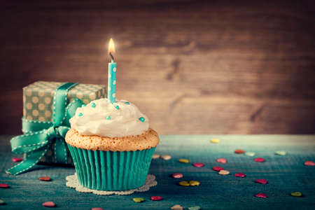 Cupcake with birthday candle and gift boxの写真素材