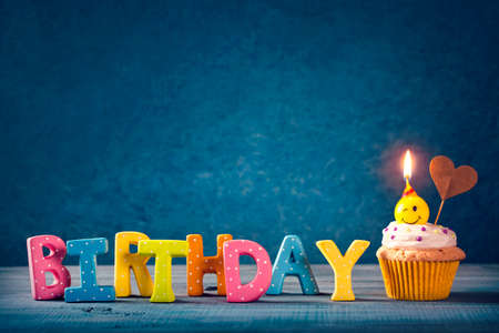 Cupcake with smiley candles and colorful balloonsの写真素材