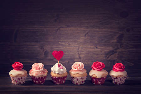 Small cupcakes with roses in a rowの写真素材