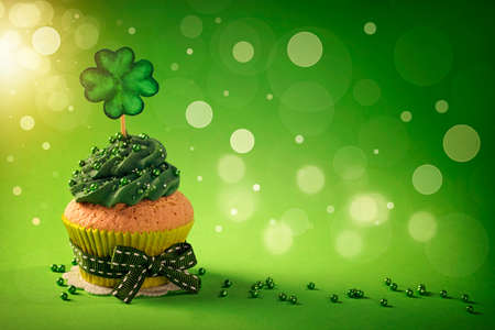 Cupcake with clover cakepick on a wooden background