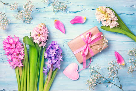 Pastel colored flowers and a gift box on a blue backgroundの写真素材
