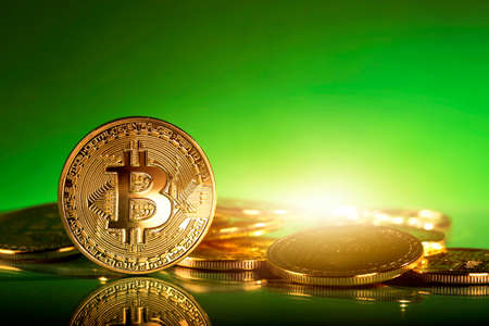 Gold bitcoins on a green backgroundの写真素材