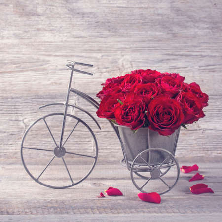 Red rose in bicycle vase on a wooden backgroundの写真素材