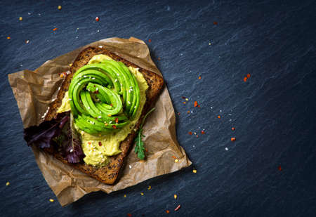 Sandwiches with rye bread, fresh sliced avocado and arugula