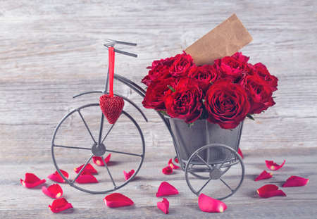 Red rose in bicycle vase on a wooden backgroundの写真素材
