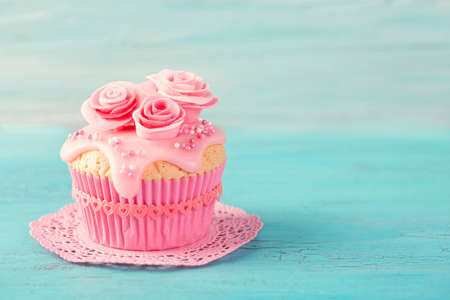 Cupcake with pink flowers on a blue wooden backgroundの写真素材