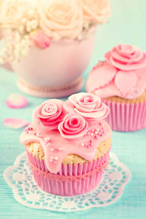 Cupcakes with pink flowers on a blue wooden backgroundの写真素材